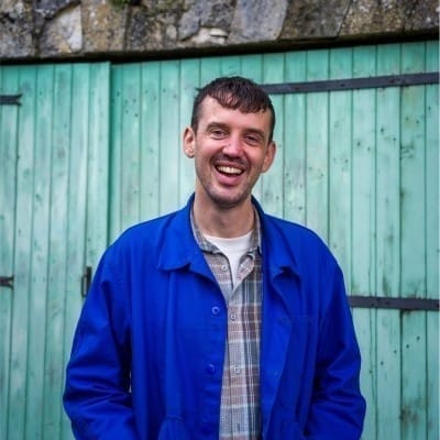 A photo of Ben Whitelaw, founder and editor of Everything in Moderation*, standing against a green gate