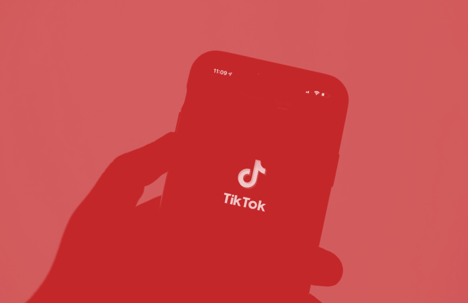 Hand wrapped around a smartphone showing the TikTok logo 